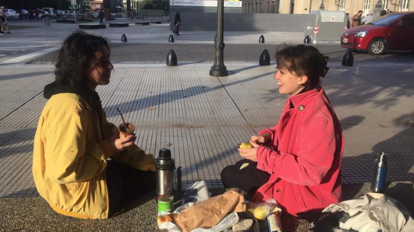 Two people eating next to a street.
