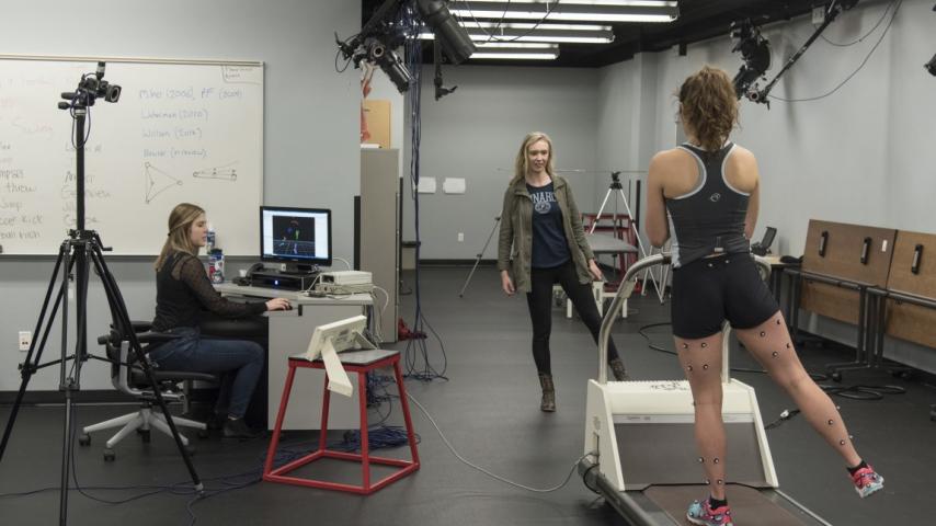 A person standing on one leg on a treadmill.
