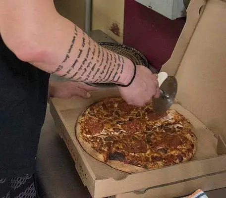 A student worker cutting a freshly baked pizza at The Cellar.
