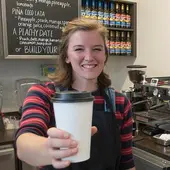 A student staff member serves a coffee at one of the campus cafes.