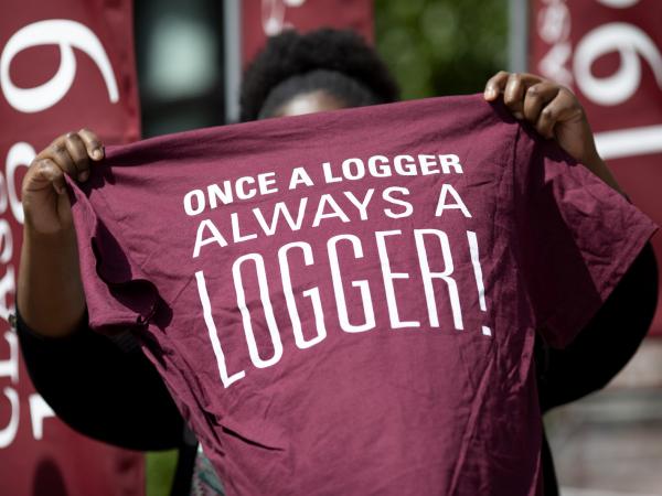 student holding up t-shirt with slogan "Once a Logger, Always a Logger"
