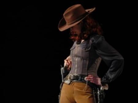 Woman in a cowboy hat ready to draw her gun
