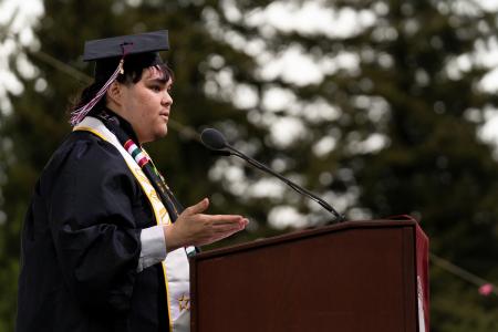 Riley Ofrecio stands at a lectern giving his commencement speech. 