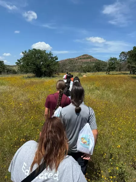 line of students walking through a meadow