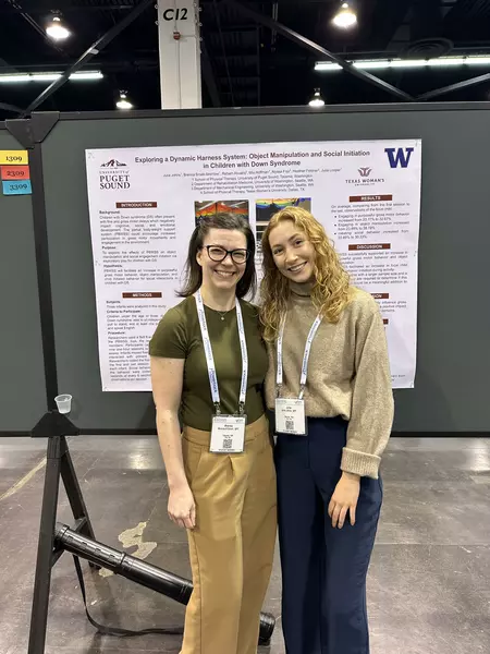 Two students pose in front a research poster. 
