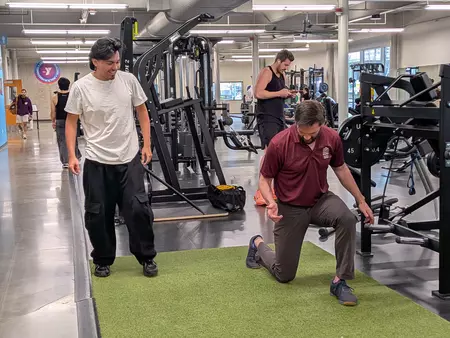 A Puget Sound PT student instructs a high school student on proper form in the weight room. 