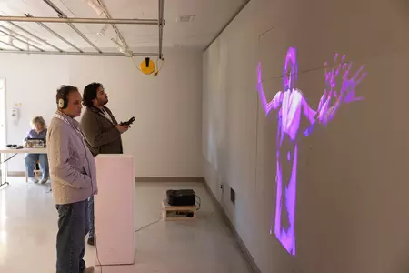Two men view an artificial intelligence interactive art piece