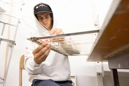 Roy Kersten-Hellikson ’27 weaving on metal frames