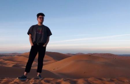 A person standing in front of sand dunes.
