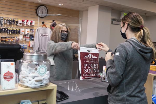 A shopper makes a purchase at the Logger Store, observing mask-wearing and social distancing protocols