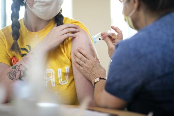 Woman in a yellow shirt getting a COVID-19 vaccine shot