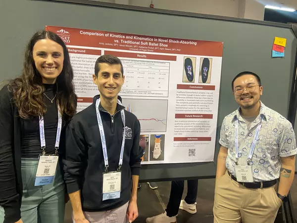 Three students pose in front of a research poster.