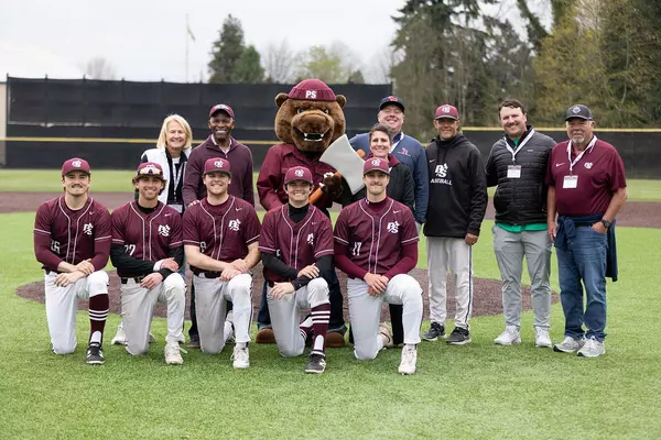 Group photo with mascot on baseball field. 