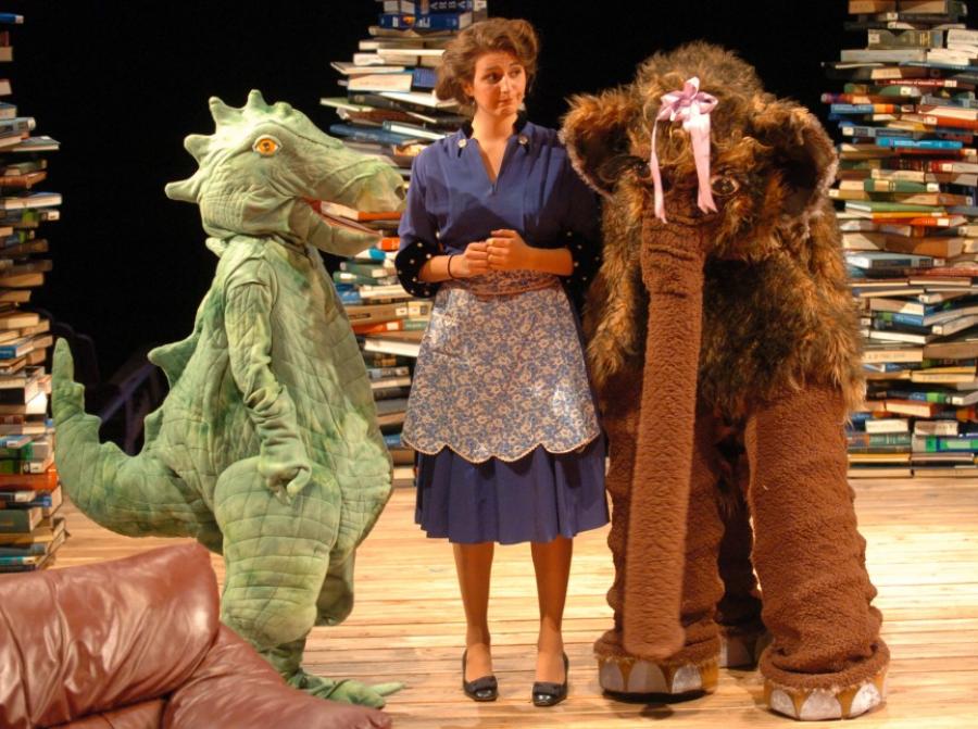 Woman elephant and alligator stand in front of stacks of books