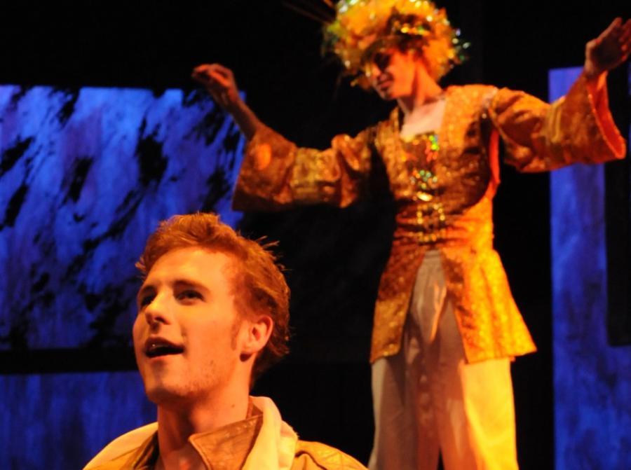 Two actors on stage in gold-colored costumes